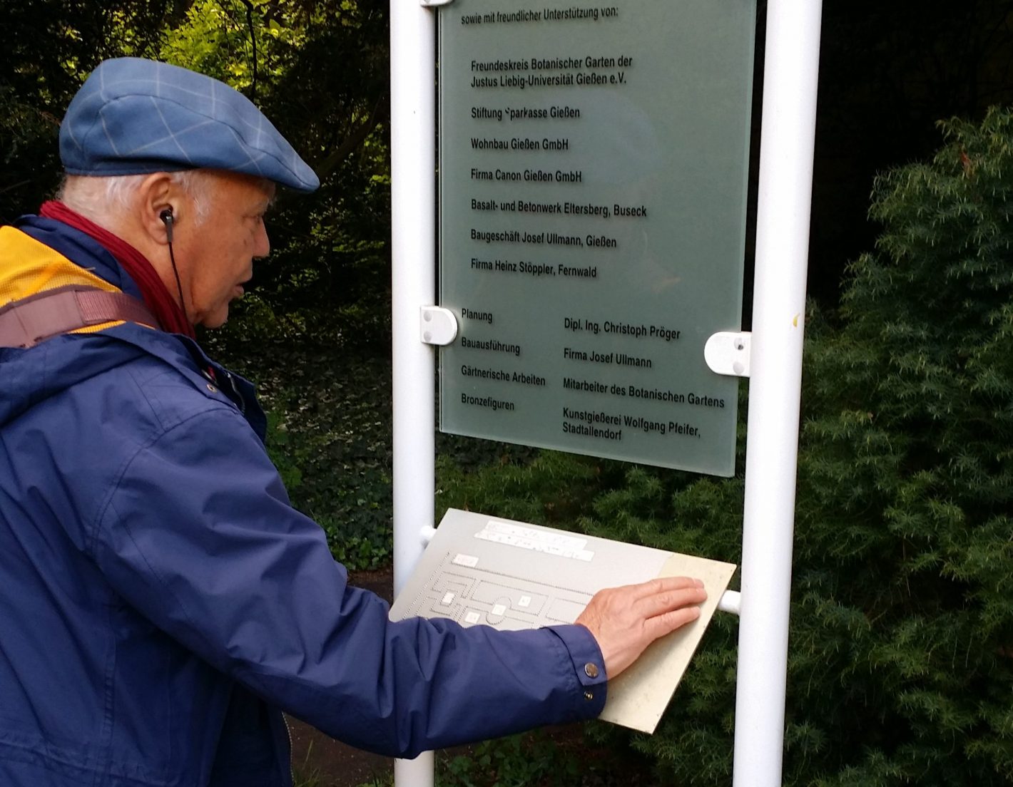Mustapha Ouertani liest Braillebeschriftung des Übersichtsplans im Botanischen Garten in Gießen