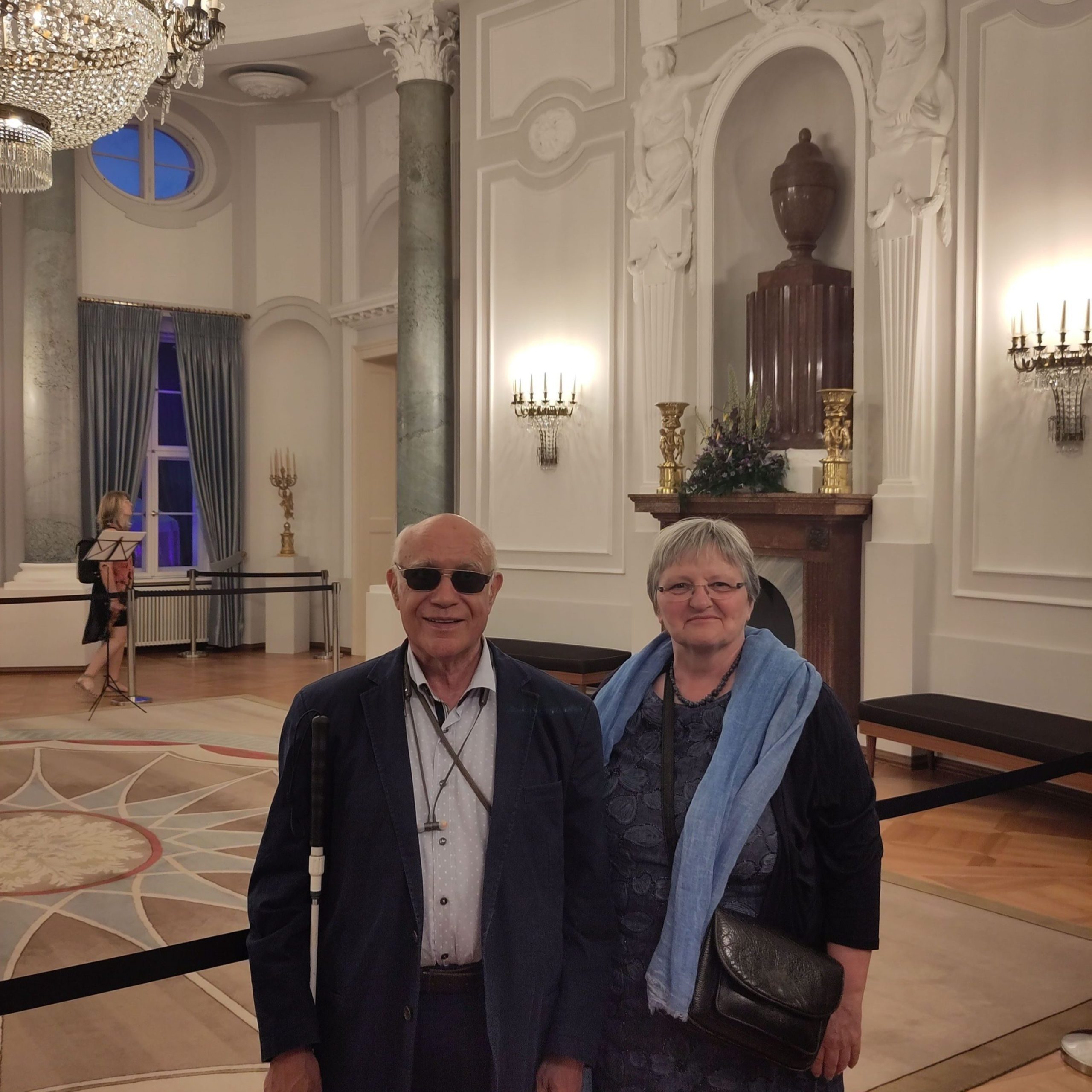 Vereinsgründer Dr. Mustapha Ouertani und Vereinsvorsitzende Bernadette Smyrek Ouertani stehen in einem Saal im Schloss Bellevue in Berlin.  